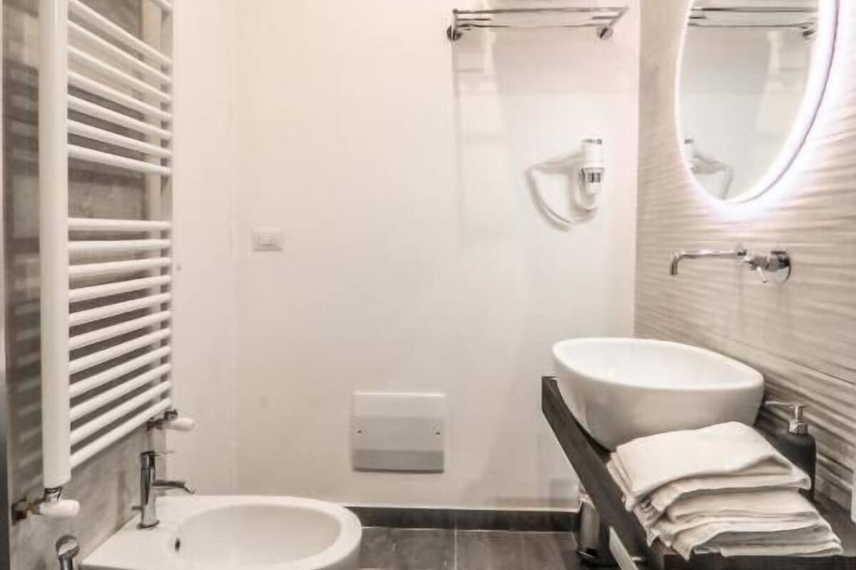 A modern bathroom with two sinks, a shower, and a vanity with a mirror.
