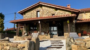 A stone house with a tiled roof, a porch with outdoor seating, and a gravel pathway leading to the entrance. - La Biescona de Llúces d'Ítaca - Connection and rootedness (Luces (Lastres)