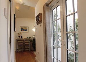A hallway with a dining area, a wooden chair, a table, and a potted plant.