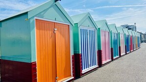 En rad färgglada strandhytter med en stadsbild i bakgrunden.