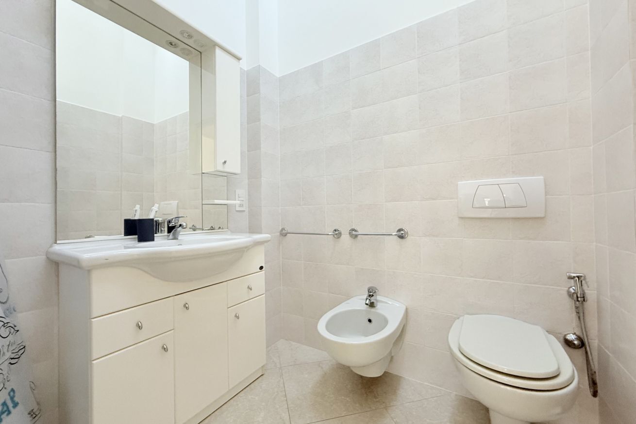 A modern bathroom with a white vanity, bidet, and toilet.