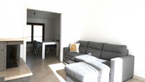Een moderne woonkamer met een bank, een bijzettafeltje en een open haard.