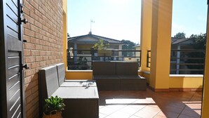 Een balkon met rieten meubilair en een potplant.