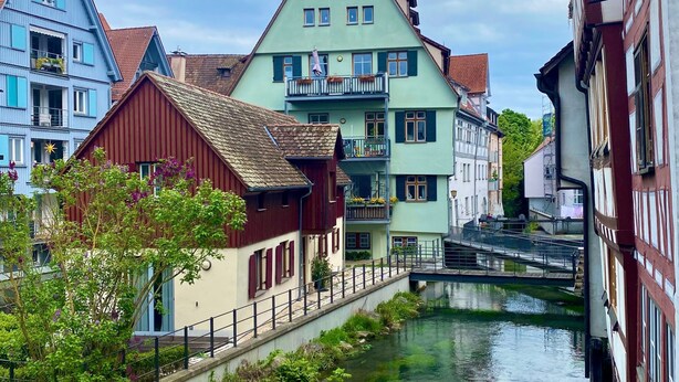 Ein Kanal mit Gebäuden an beiden Seiten, eine Brücke und ein klarer Himmel.