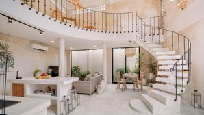 Un vaste espace de vie comprenant un escalier en colimaçon, une table à manger avec des chaises et un canapé.
