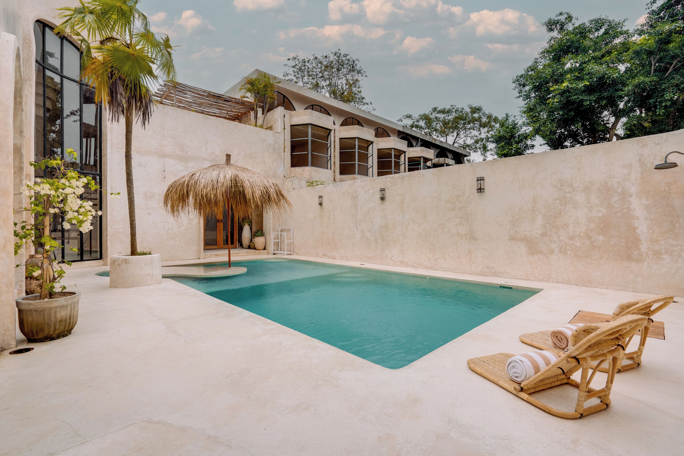 A swimming pool with lounge chairs and a thatched umbrella.