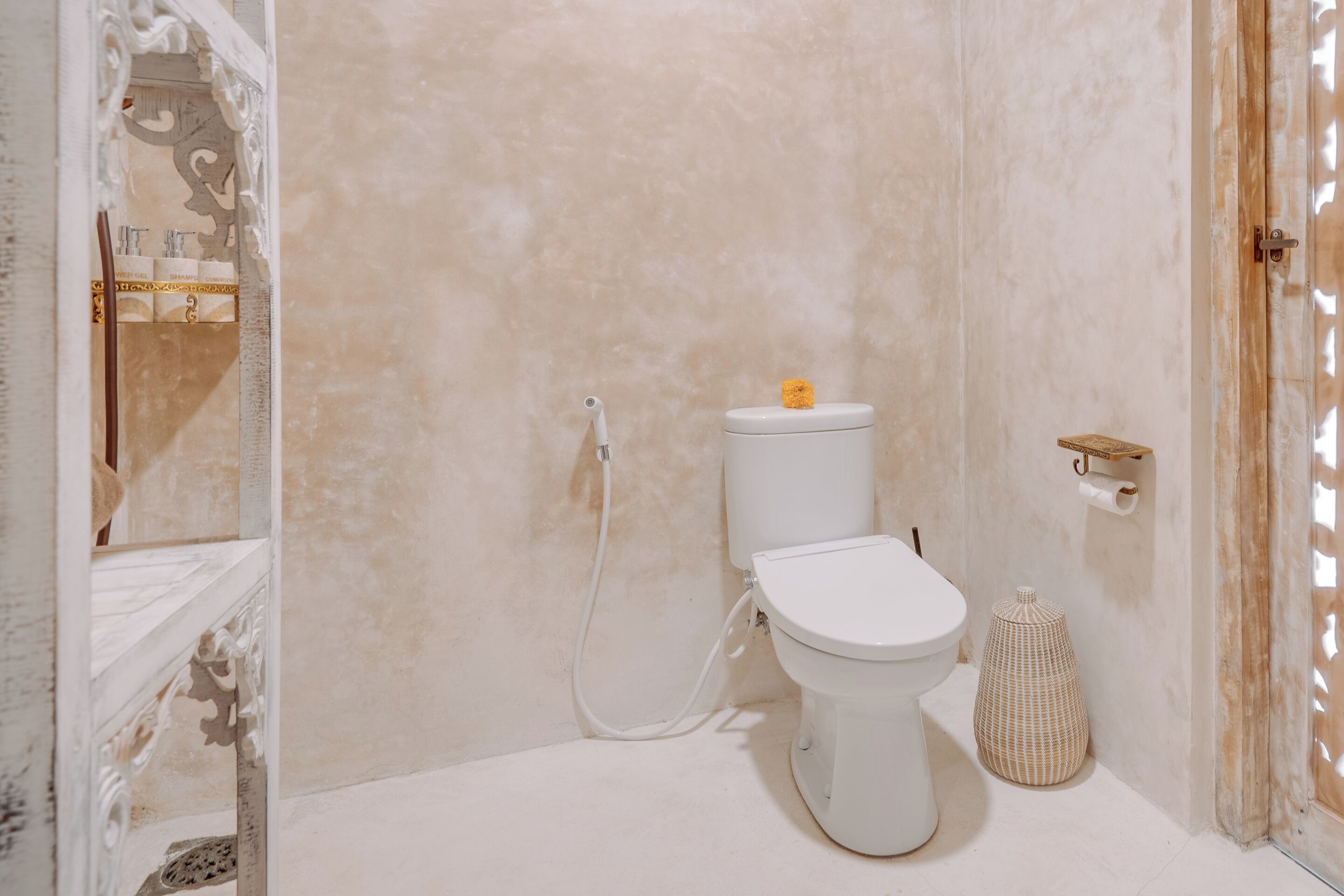 A bathroom with a toilet, bidet, and a decorative mirror.