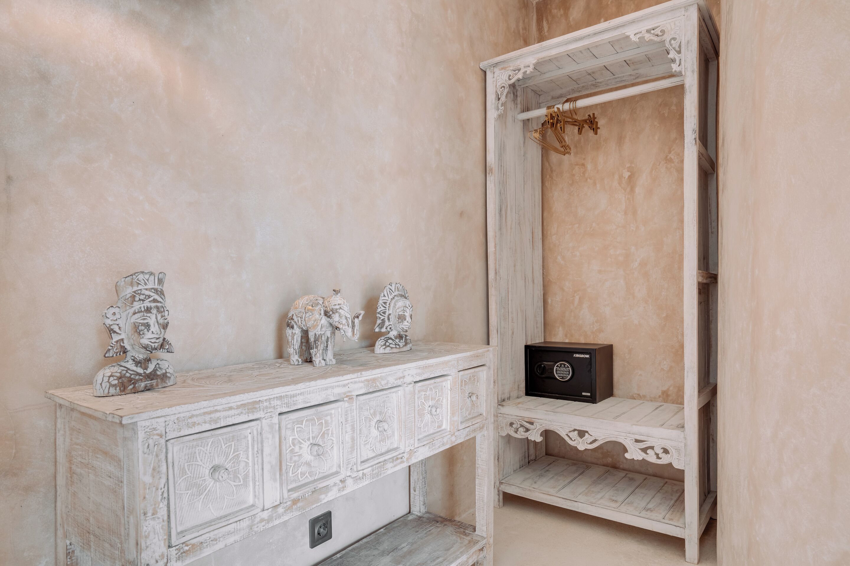A white, ornate dresser with decorative figures and a small black box.