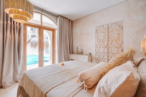 Un dormitorio con una cama grande, vista a una piscina y un panel decorativo en la pared.