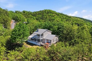 A two-story house with a balcony, surrounded by dense forest. - Dog Friendly Cabin|Hot-tub & VIEWS|Near Dollywood (Sevierville)