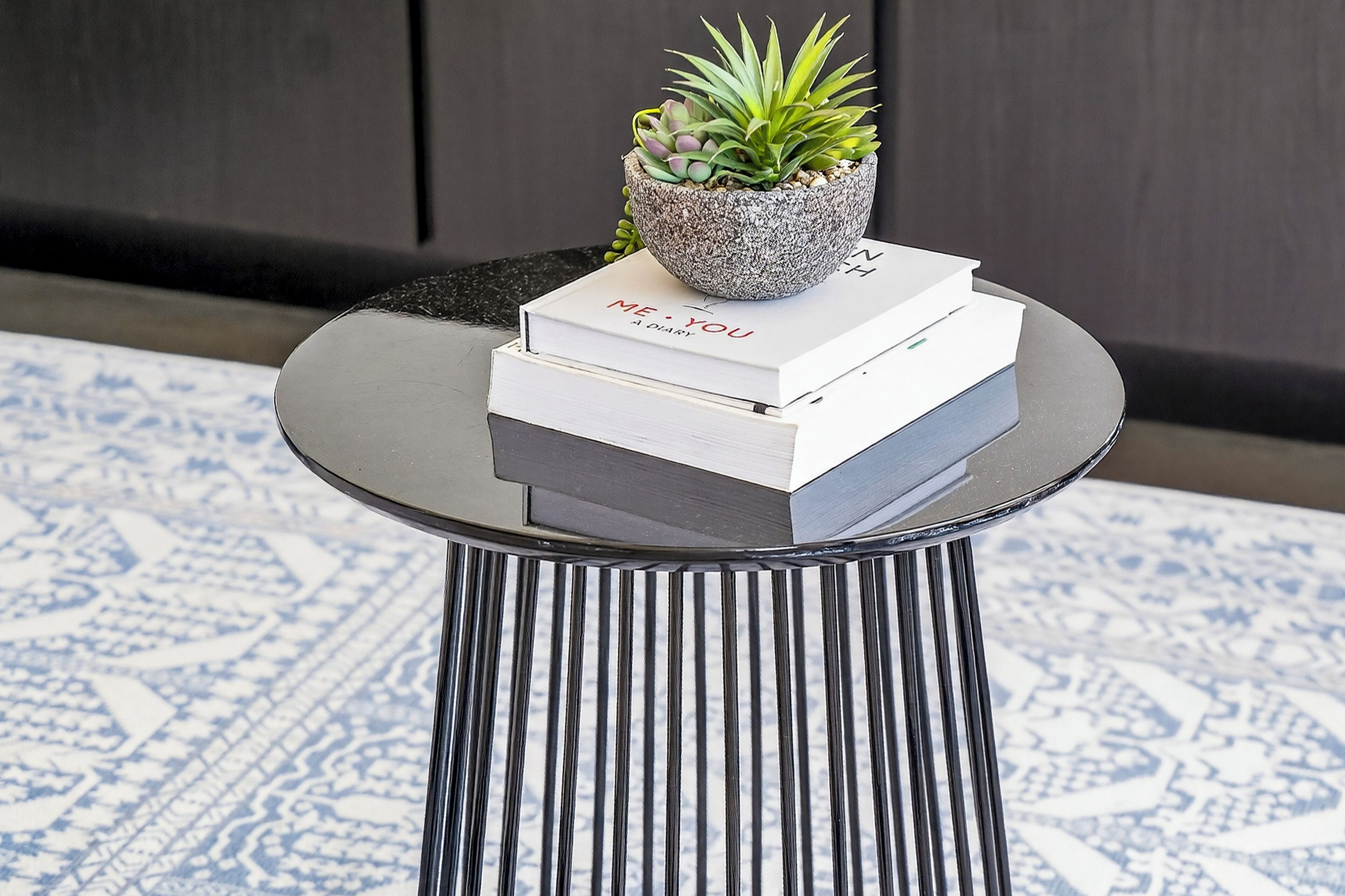 A round table with a potted plant and books on top.