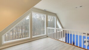 A spacious attic room with large windows, a wooden floor, and a blue accent wall. - 4 Mi to Charming Dtwn Fayetteville! Bright Home (Fayetteville)