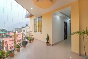 A spacious corridor with potted plants, a view of the cityscape, and a modern interior design. - Saalak Lite By Divine Dev Darshan  (Rishikesh)