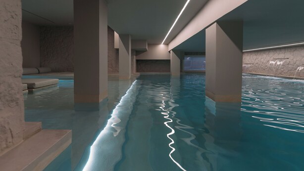 Una piscina interior con agua cristalina, sostenida por columnas e iluminada con luces del techo.