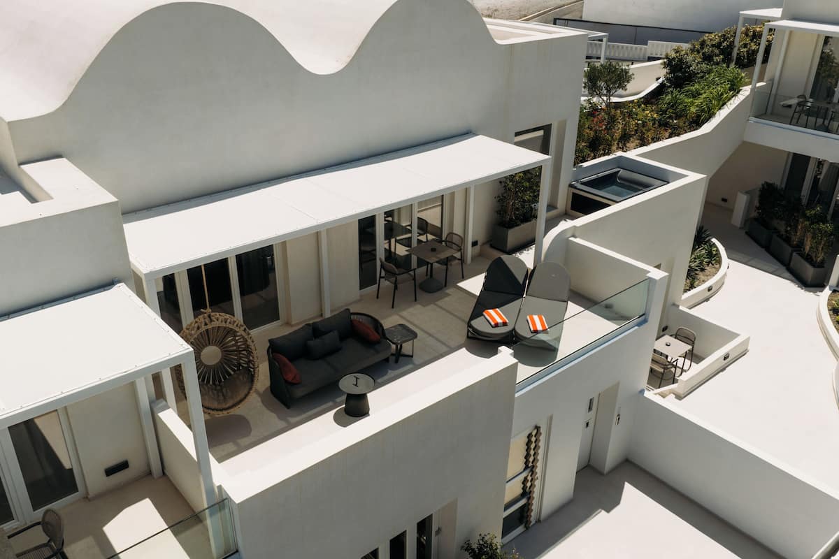 A modern building with a rooftop patio, outdoor seating, and a glass balustrade.