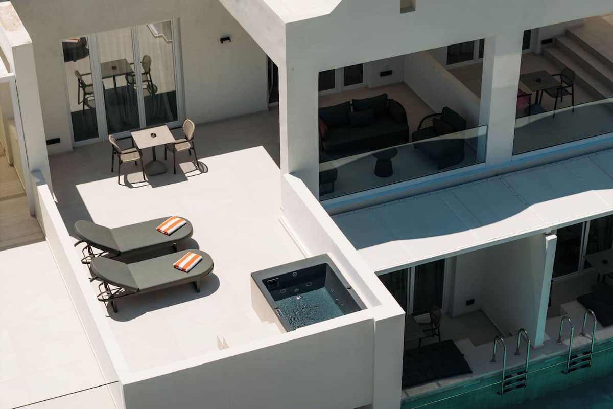 A modern rooftop with a pool, lounge chairs, and a seating area.