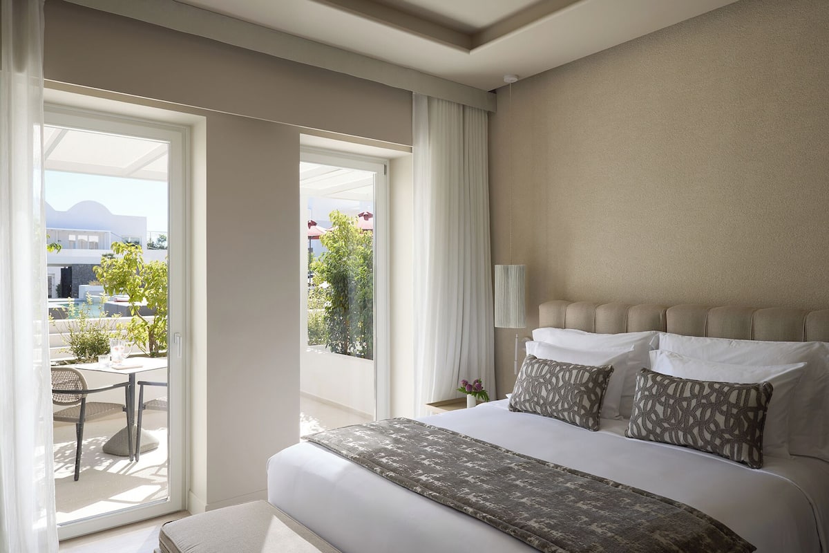 A hotel room with a bed, a view of the outdoors, and a balcony.