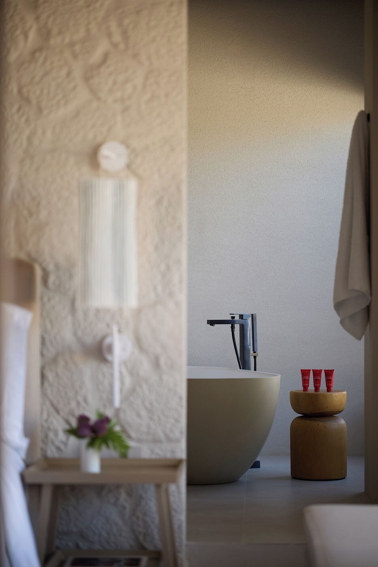 Un baño con bañera, lavamanos y una pequeña mesa con un florero.