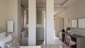 Un dormitorio moderno con cama, mesita de noche y una zona de escritorio con silla.