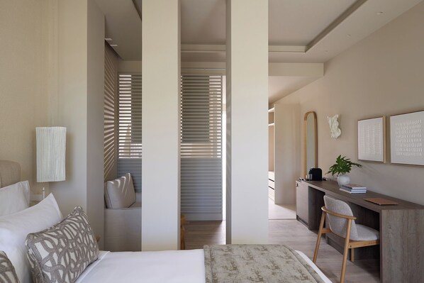 A modern bedroom with a bed, bedside table, and a desk area with a chair. - Santorini Heart Hotel & Spa (Santorini)