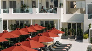 Un resort con varias zonas de descanso, mobiliario exterior y una piscina.