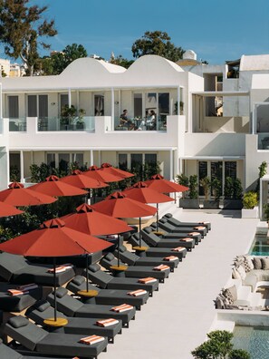 Un resort con varias zonas de descanso, mobiliario exterior y una piscina.