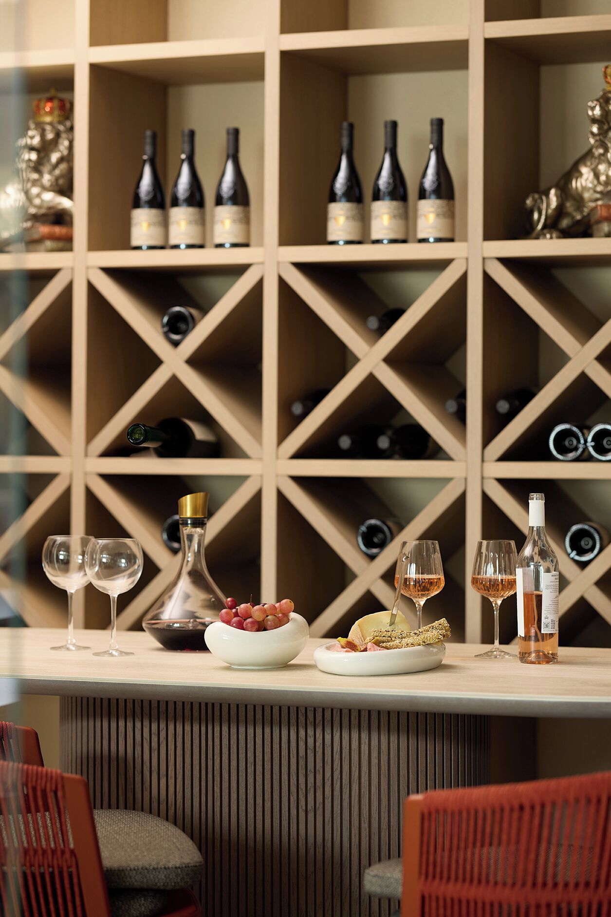 A wine cellar with shelves of wine bottles and glasses on a table.