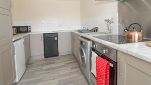 A compact kitchen with a dishwasher, microwave, kettle, and a stainless steel range hood. - Lavender Lodge (Hull)