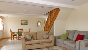 A living room with a beige sofa, a grey sofa, a glass coffee table, and a wooden staircase. - Lavender Lodge (Hull)