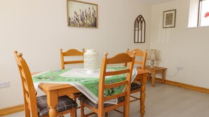 A dining area with a table set for four, surrounded by wooden chairs with plaid cushions. A white lantern and a table lamp are on the table. - Lavender Lodge (Hull)