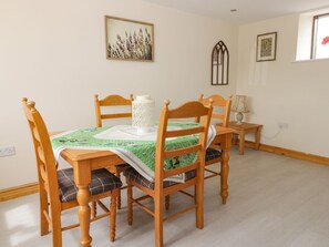 A dining area with a table set for four, surrounded by wooden chairs with plaid cushions. A white lantern and a table lamp are on the table. - Lavender Lodge (Hull)