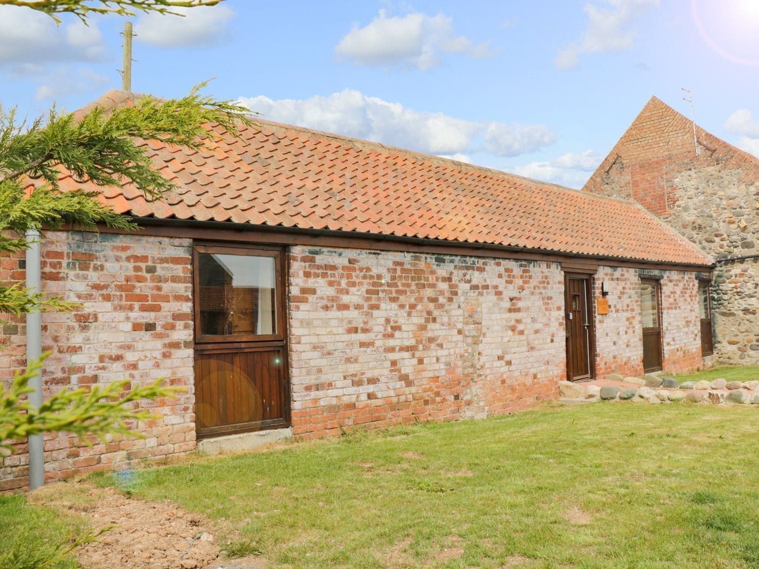 A brick building with a tiled roof, a wooden door, and a window.