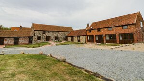 Une cour bordée de bâtiments en pierre, un chemin de gravier et une zone herbeuse.