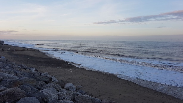 Une plage avec un rivage rocheux et un ciel dégagé.