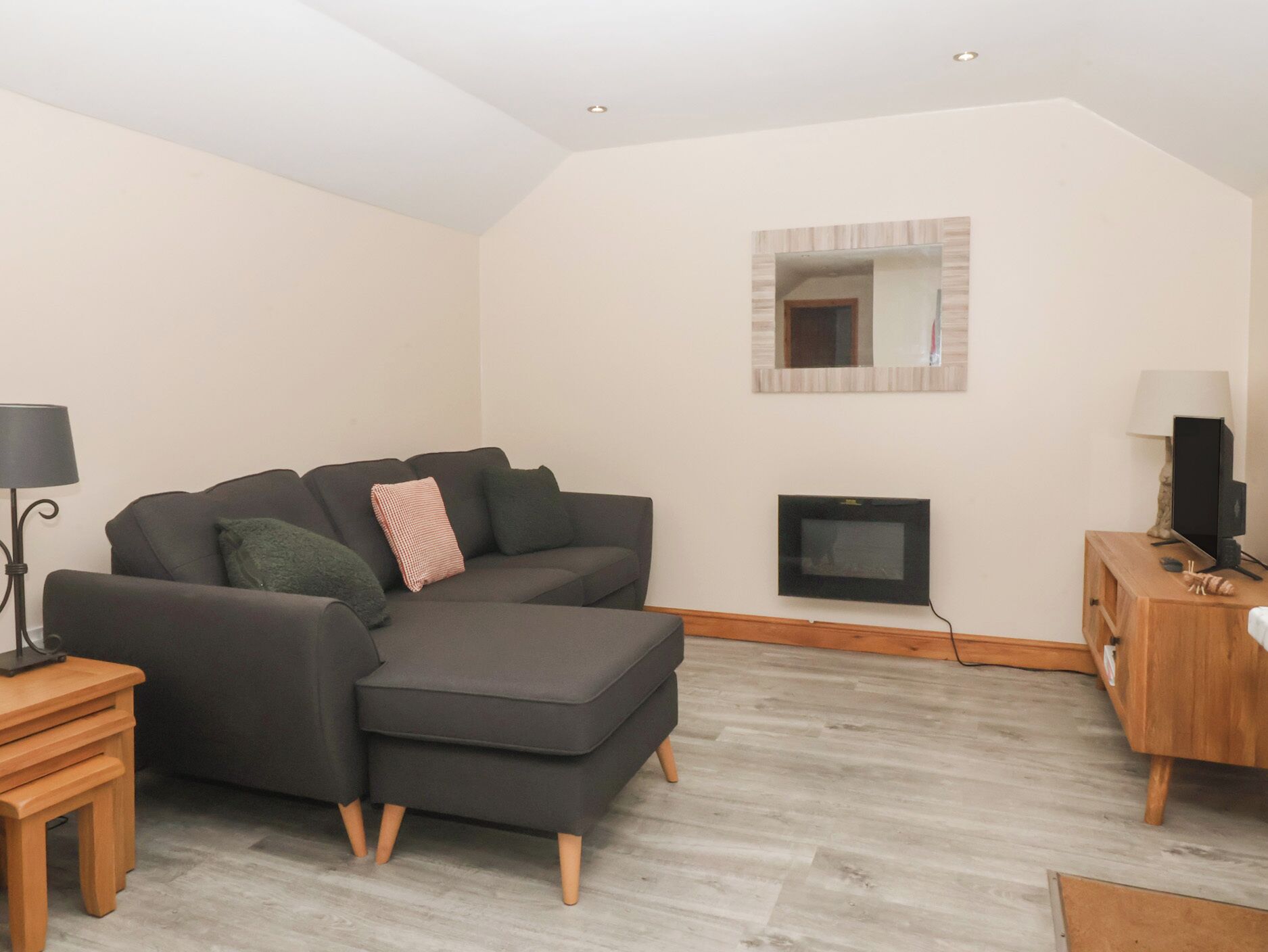 A modern living room with a sofa, a TV, and a wooden cabinet.