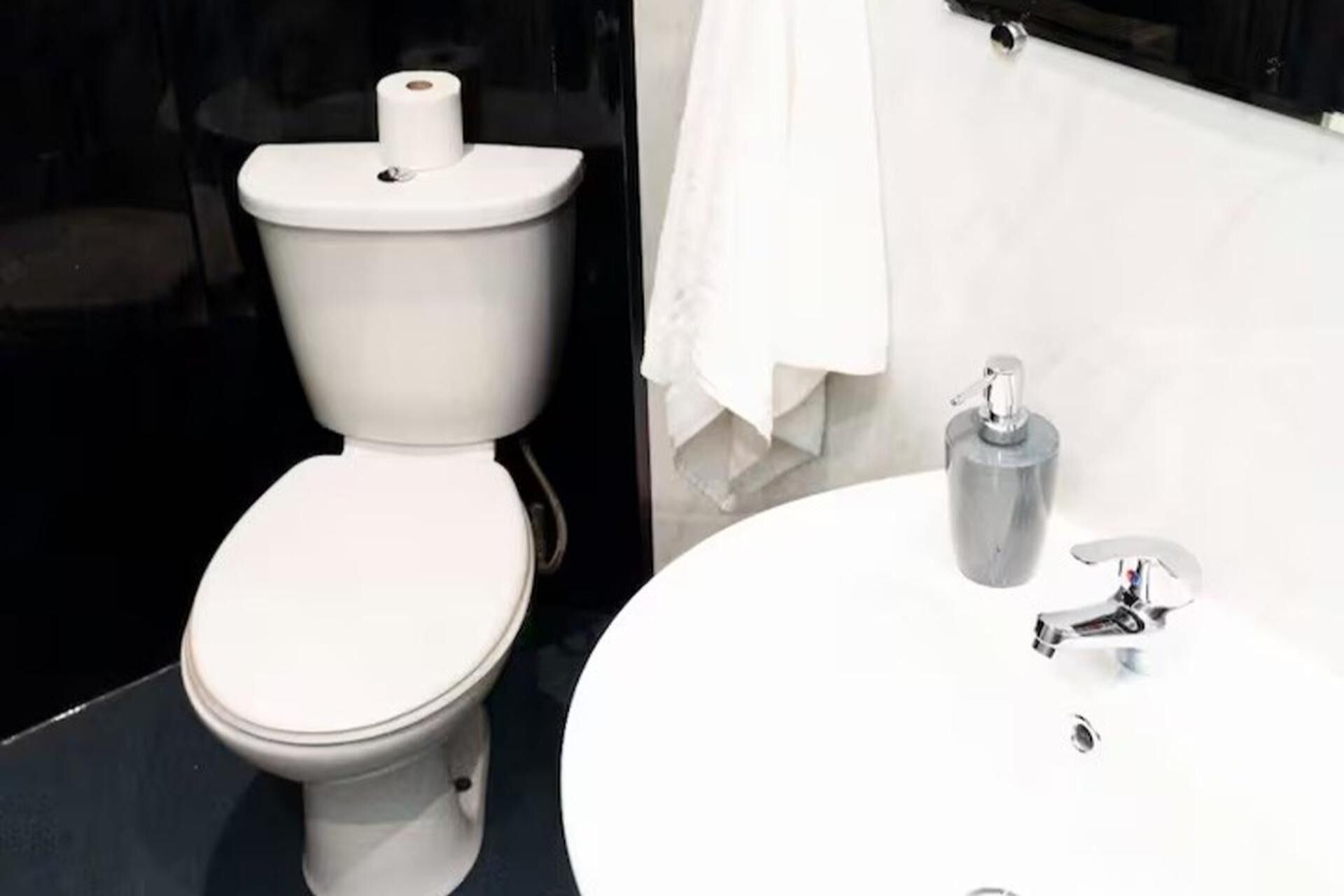Une salle de bain moderne avec des toilettes, un lavabo et une serviette accrochée au mur.