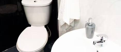 Une salle de bain moderne avec des toilettes, un lavabo et une serviette accrochée au mur.
