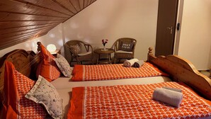 Una habitación acogedora con dos camas, una mesita, dos sillas y un armario.
