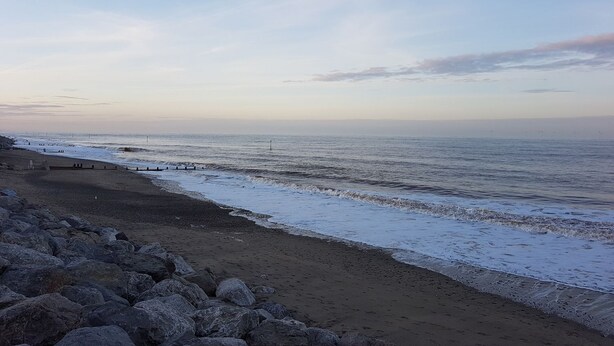 Une plage avec un rivage rocheux et un ciel dégagé.