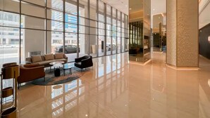 A modern lobby with a glass partition, seating area, and a polished floor. - Vogue | Downtown near Dubai Mall | Burj Khalifa (Dubai)