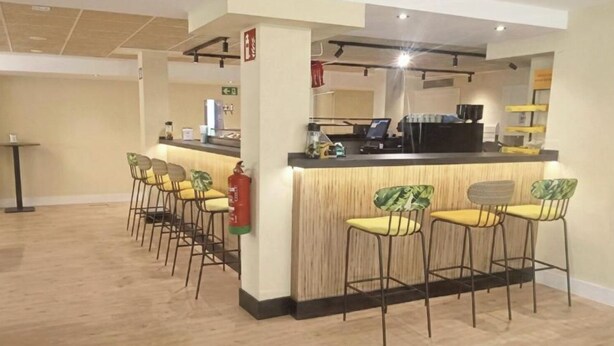 Zona de bar con mostrador, taburetes y extintor.