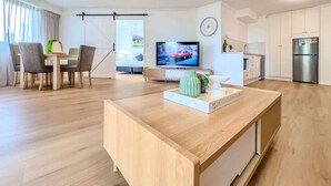En moderne stue med et træsofabord, et fjernsyn og et spiseområde med stole og et bord.