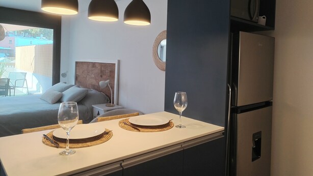 Een moderne keuken met een eethoek, met een koelkast, hanglampen en uitzicht naar buiten.