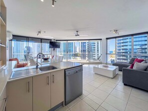 Eine moderne Wohnung mit Küche, Essbereich und Wohnzimmer, ausgestattet mit großen Fenstern und Blick auf die Stadt.