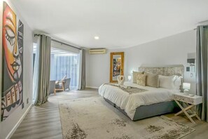 A modern hotel room with a large bed, a desk, and a view of the city. - Luxury Home w/pool in Bryanston (Sandton)