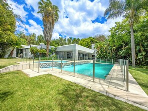 A modern house with a swimming pool, surrounded by lush greenery and a clear blue sky. - Luxury Home w/pool in Bryanston (Sandton)