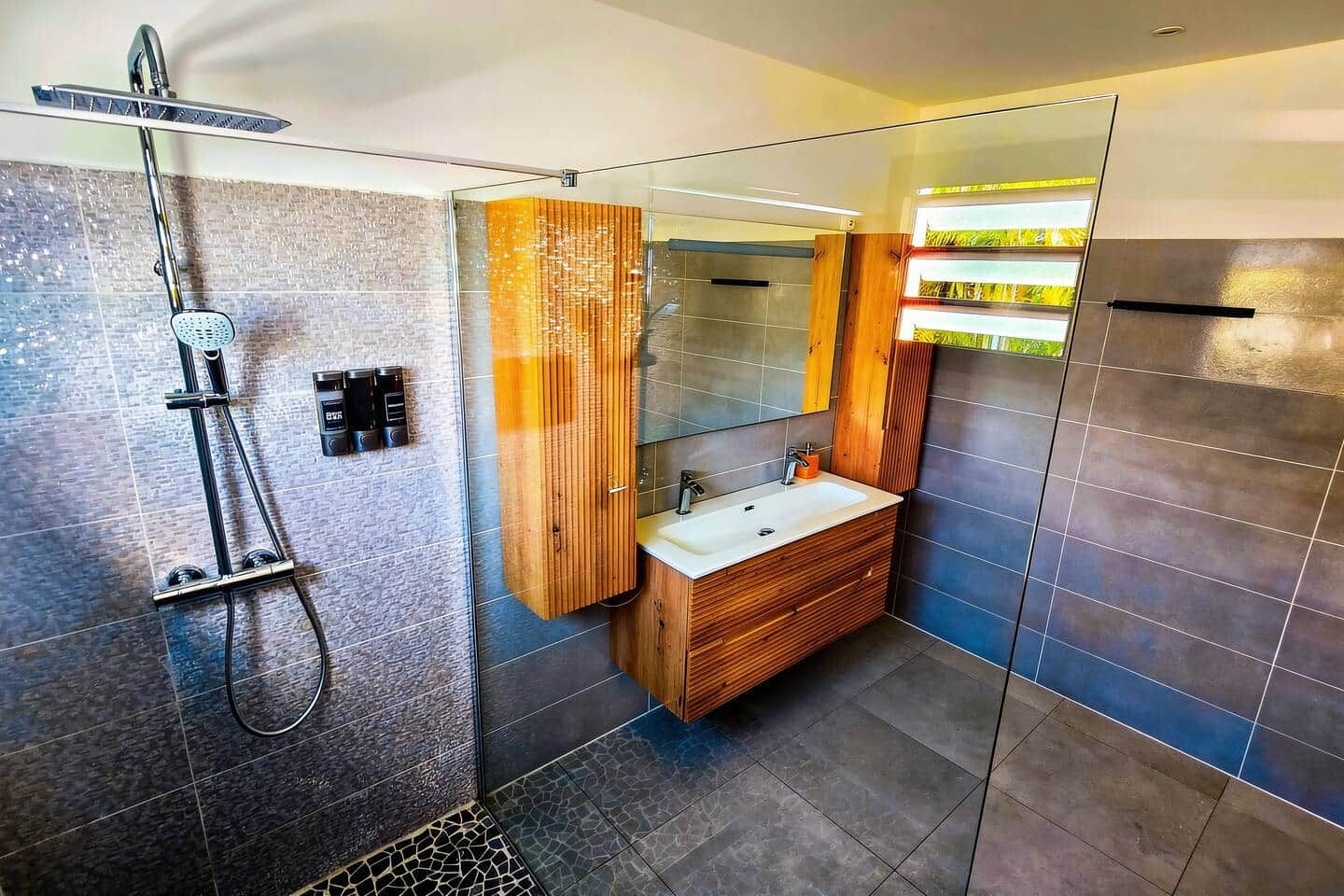 A modern bathroom with a shower, a sink, and a mirror.