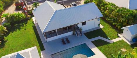 A modern house with a swimming pool, a covered patio, and a well-maintained lawn.