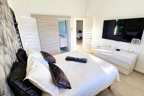 A hotel room with a bed, a TV, a dresser, and a walk-in closet. - Villa Kynoa 4 stars (Saint-François)