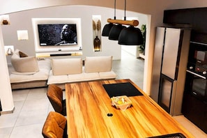 A modern kitchen with a wooden dining table, a built-in oven, and a large flat-screen TV. - Villa Kynoa 4 stars (Saint-François)
